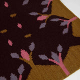 Detail of Hedgerow flatweave rug handwoven in dark brown with mustard yellow decorative border and pink and lilac accents.
