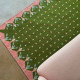 Green and pink hedgerow flatweave rug handwoven with pink decorative border and motifs.
