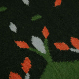 Detail of dark forest green hedgerow rug with contrast light blue and coral accents.