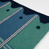 Detail of blue and green runner rug with wavy navy border