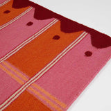 Detail of Pink and orange runner rug handwoven in vibrant shades with wavy border.