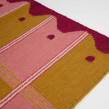 Detail of pink and yellow ladder runner with wavy border and checkered pattern.
