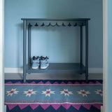 Light blue hallway with Blue Runner Rug, handwoven with a geometric zig zag border and star motifs and magenta pink accents.