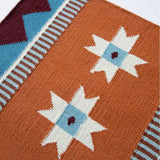 Detail of flatweave runner rug, handwoven from wool in orange with blue and claret accents in a geometric design inspired by Victorian tiles.