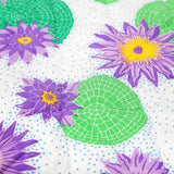 Detail of hand quilted lily lotus baby quilt with vibrant green lily pads and purple and yellow lily flowers.