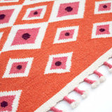 Detail of Orange Evil Eye Flatweave Wool rug with pink tassel edge