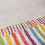 Detail of Rainbow Rug border handwoven in bright colourful shades of yellow, orange, pink, purple, blue and green.