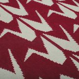 Detail of handwoven Maroon rug handwoven in wool with grey crane motifs on a rich red base.