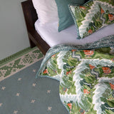 Bedroom with blue and green manali flatweave rug with green and blue quilt.