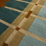 Close-up detail of Corbie handwoven flatweave wool rug showing geometric design in teal blue, light blue, ochre yellow and caramel brown tones.