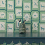 Folk Tales wallpaper in pistachio green with illustrated animal pattern shown in situ.