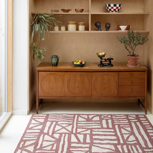 Living space with red Tudor flatweave rug handwoven in red and natural tones with a subtle graphic pattern.