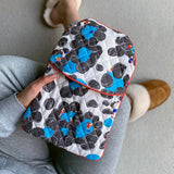 Person wearing slippers and holding a quilted cotton hot water bottle cover featuring the handprinted Rockpool seaside design.